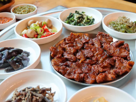 연탄고추장불고기 가까이 — 쇠 접시에 담긴 고추장 양념 불고기, 둘레 반찬